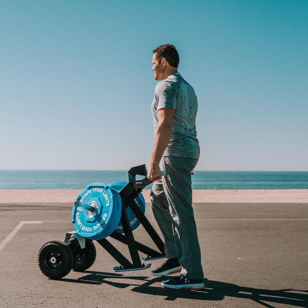 Man using Escape Fitness Barrow Sled for loaded carry and sled push workout outdoors