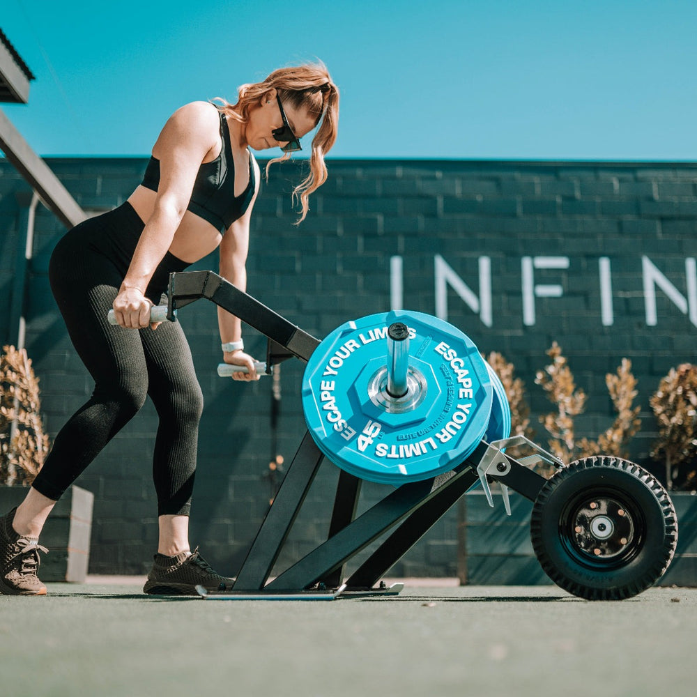 Woman using Escape Fitness Barrow Sled with blue weight plate outdoors