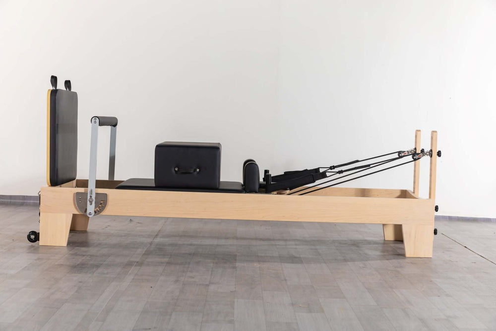 Origin Fitness Maple Wood Pilates Reformer with maple frame and black padded carriage for studio use