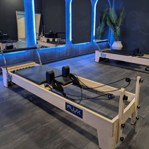 maple wood-based pilates reformer black leather in studio setting