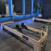 maple wood-based pilates reformer black leather in studio setting
