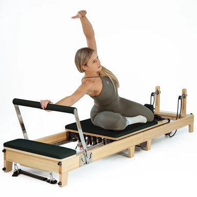 Pilates instructor using foldable maple oak reformer in professional studio setting