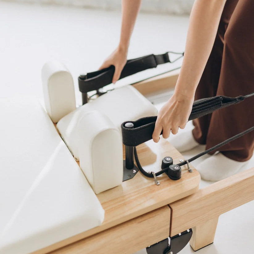 Foldable Pilates reformer showing adjustable resistance straps for studio workouts